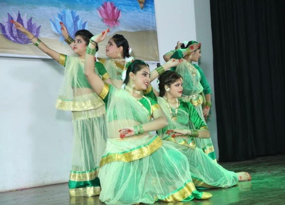 Dancers in green and gold costumes performing classical Indian dance