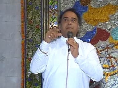 Man in white speaking at microphone at a decorated cultural event