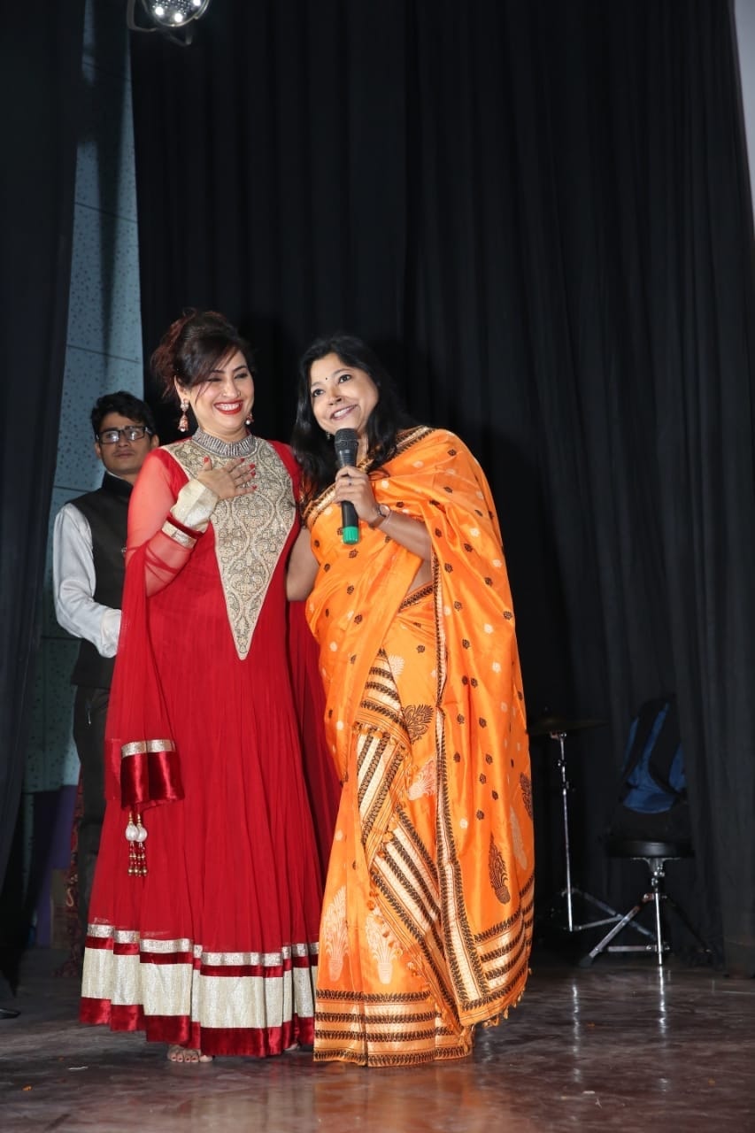 Two women in traditional attire on stage at cultural event