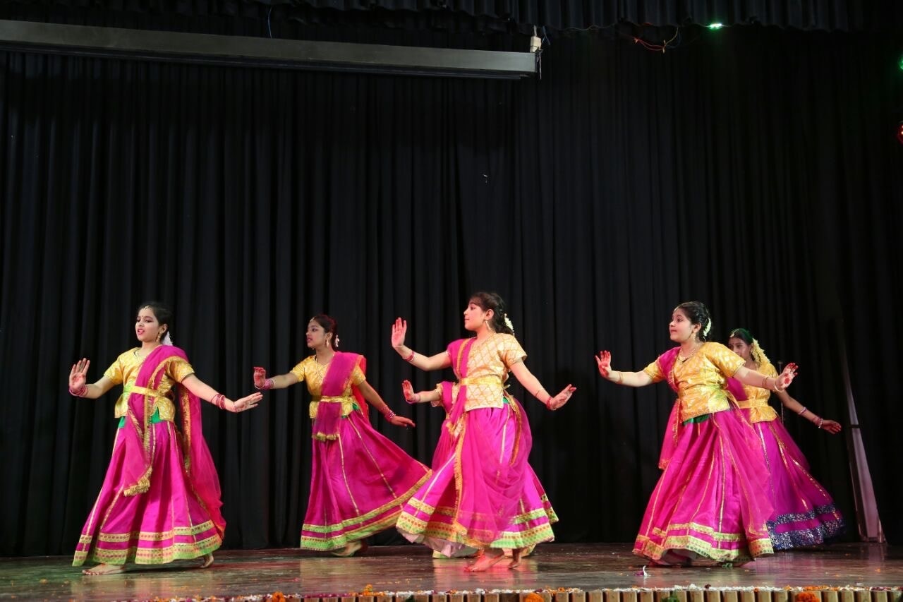 Group of dancers in pink and gold costumes performing on stage