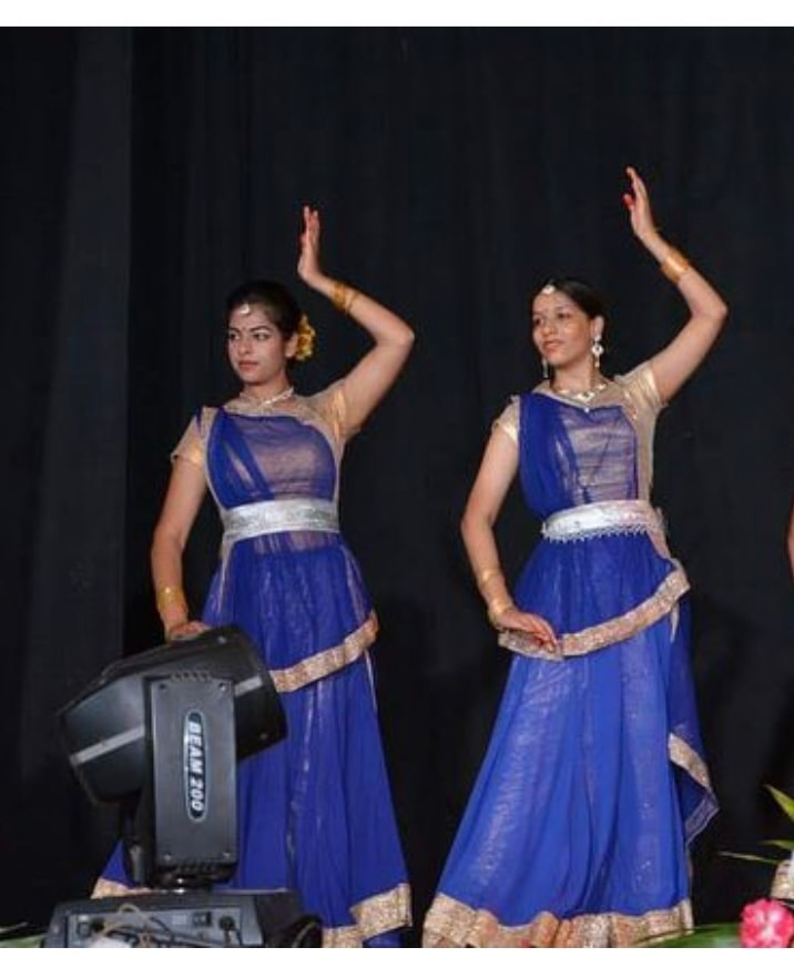 Two dancers in royal blue lehengas performing on stage