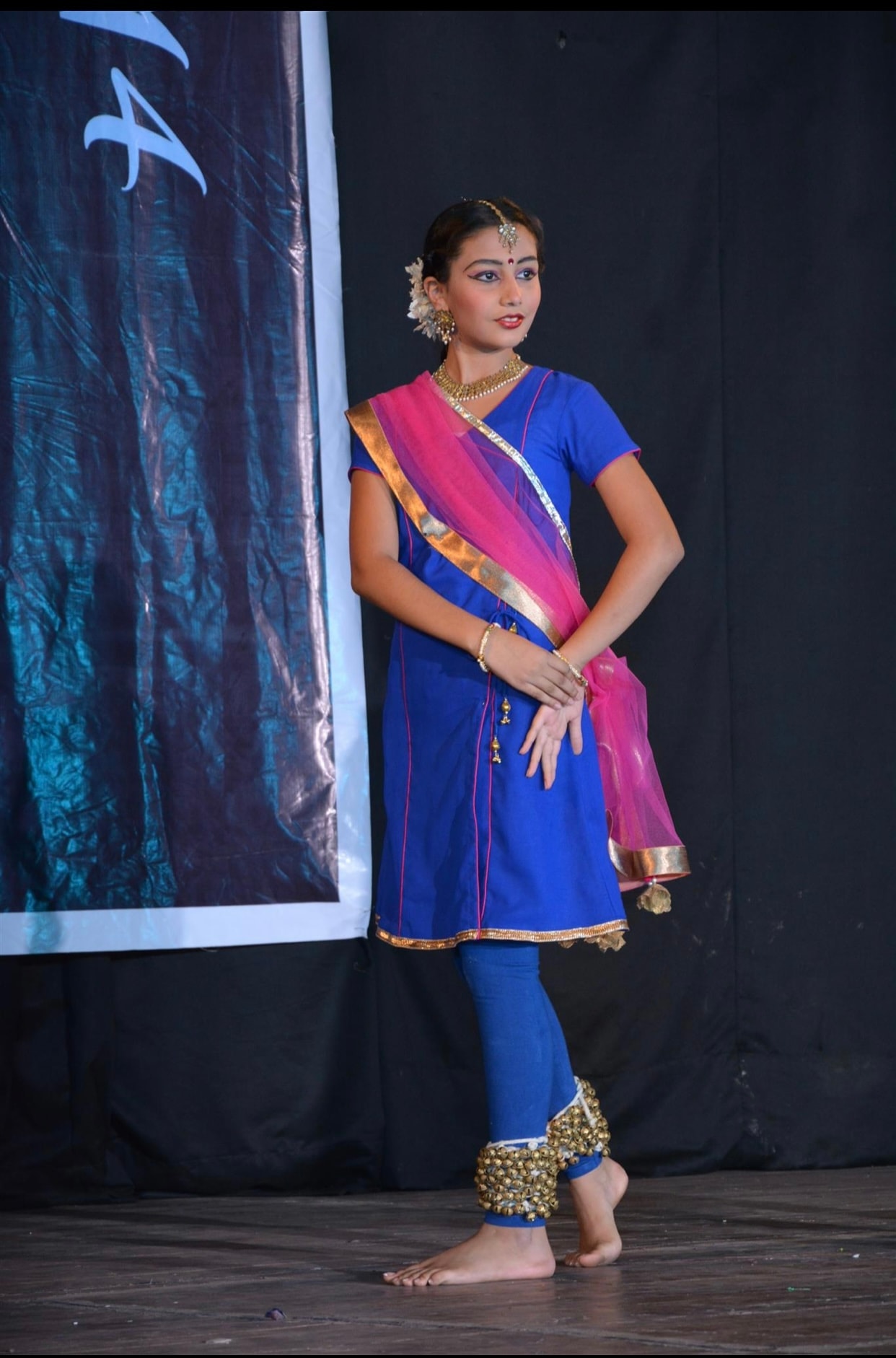 Solo dancer in blue and pink costume with ghungroo on stage