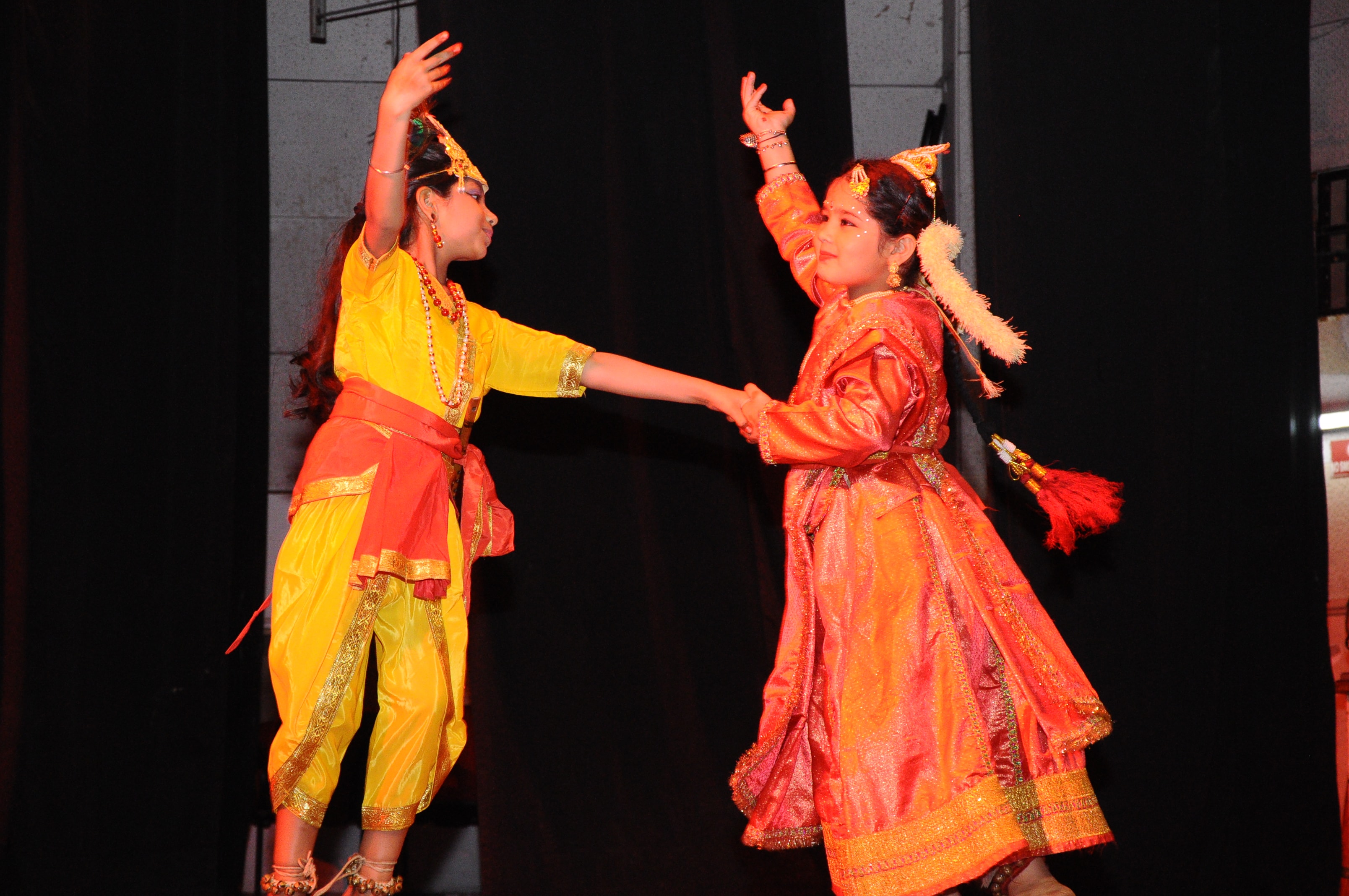 Two students in yellow and red performing classical dance